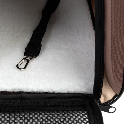 Intérieur d’un sac de transport pour animaux avec tapis en tissu blanc, sangle noire et mousqueton métallique visibles.