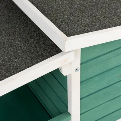 Detailansicht eines grünen Holz-Tierhauses mit weissem Rahmen und grauem Dach aus wetterfestem Material.