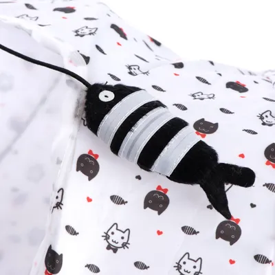 Schwarzes Stoffspielzeug in Fischform mit silbernen Streifen auf weissem Hintergrund mit Katzen- und Herzmotiven.
