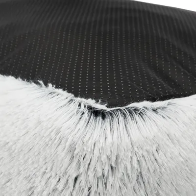 Close-up van een antislip onderkant met zwarte stippen en witte kunstbont rand. Geschikt voor dierenbedden of dekens.