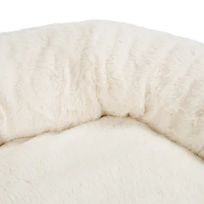 Gros plan sur la surface d’un panier pour animal en tissu peluche blanc cassé, sans marque visible ni autres éléments distinctifs.