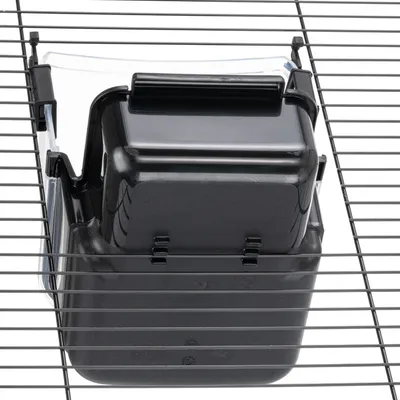 Zwarte kunststofbox met clips, bevestigd aan metalen tralies. Geschikt voor kooien of hokken.