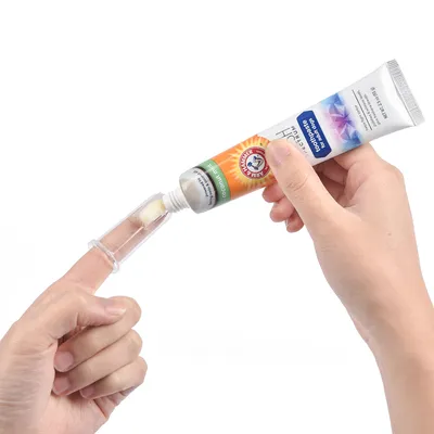 Applicering av tandkräm för husdjur med fingerfäste. Tub med synlig logotyp 'Arm & Hammer' och smak av kokosnöt.
