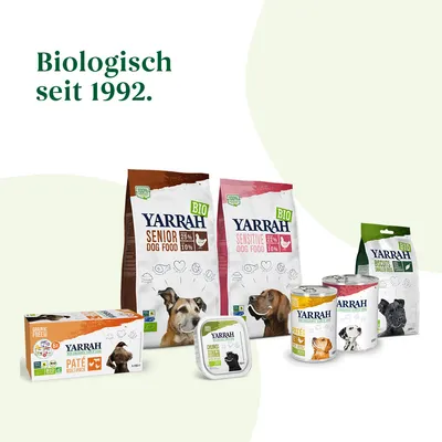 Ассортимент кормов для собак Yarrah: сухие и влажные корма, лакомства. Видны упаковки с надписями BIO, SENIOR DOG FOOD, SENSITIVE DOG FOOD, BISCUITS, PATÉ, CHUNKS. Текст: Biologisch seit 1992.