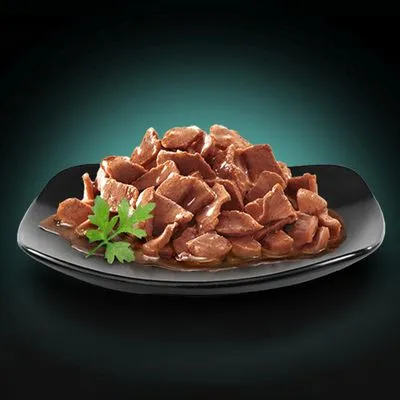 Portie natvoer in stukjes op zwart bord met saus en peterseliegarnituur, zonder zichtbare merknaam of verpakking.