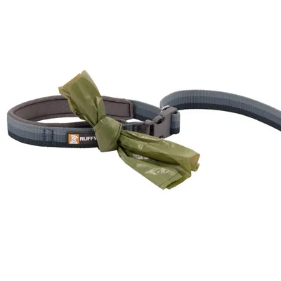 Hondenhalsband en lijn van textiel met zichtbaar label 'RUFFWEAR', voorzien van een groene poepzakje aan de halsband geknoopt.