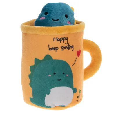 Plyšová hračka ve tvaru žlutého hrnku se zeleným motivem dinosaura a textem 'Happy keep smiling'. Obsahuje modré plyšové zvířátko s usměvavým obličejem.