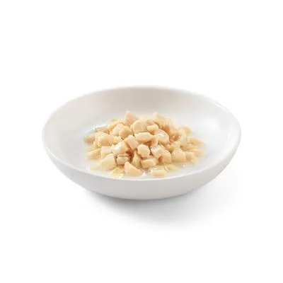 Wit keramisch schaaltje met stukjes natvoer in saus, lichtbeige van kleur. Geen merknaam of tekst zichtbaar.