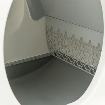Binnenkant van een kattenbak met grijze kunststof bodem en rooster aan de zijkant, zonder zichtbaar kattengrit of accessoires.