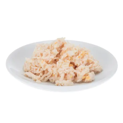 Ración de comida húmeda para mascotas servida en un plato blanco, textura desmenuzada y color claro. No se observan marcas ni ingredientes identificables.