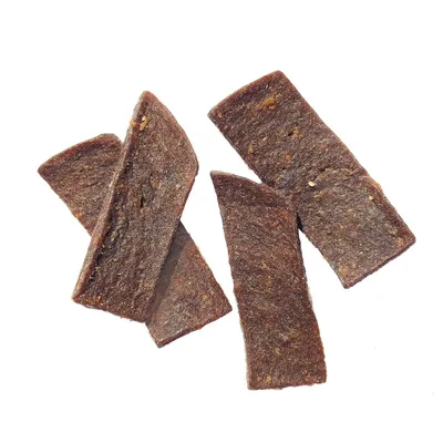 Četiri smećkasta pravokutna pseća snacka od sušenog mesa, bez vidljive ambalaže ili oznake marke.