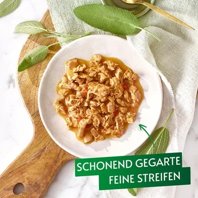 Schonend gegarte feine Streifen in Sauce, serviert auf einem weißen Teller mit Salbeiblättern und Holzbrett im Hintergrund.