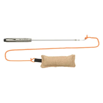 Träningspinne i metall med svart handtag, orange lina och fastsatt beige bitkudde i grovt tyg. Alla delar synliga mot vit bakgrund.