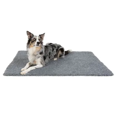 Hund liegt auf einer grauen, flauschigen Matte. Produkt zeigt Nutzung als Liegefläche für Haustiere.