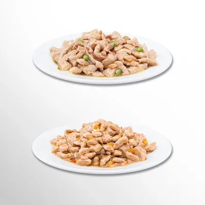 Kaksi valkoista lautasta, joilla märkäruokaa paloina kastikkeessa; ylemmässä vihreitä herneitä, alemmassa oransseja paloja. Tuotemerkki ja tarkempi sisältö eivät näy.