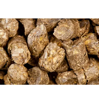 Close-up of compressed brown food pellets with visible flakes, showing texture and composition for product identification.