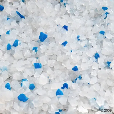 Granuli bianchi e blu di lettiera per gatti, materiale cristallino visibile in primo piano.
