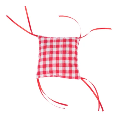 Punavalkoruudullinen tyyny, jossa punaiset nauhat kulmissa, sopii kiinnittämiseen tai koristeluun.