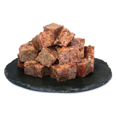 Ułożone w stos kostki mięsa na czarnej płycie łupkowej, surowe i soczyste.