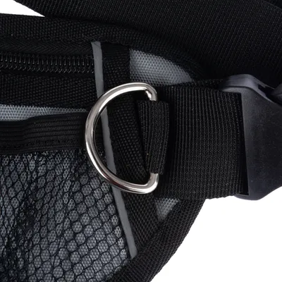 Gros plan sur un harnais en tissu noir avec boucle métallique et maille filet visible, fermeture à clip en plastique noir.