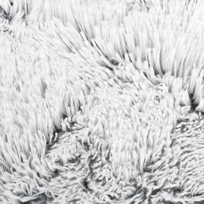 Nahaufnahme von weissem, flauschigem Material mit grauen Akzenten. Zeigt die Textur eines Produkts, möglicherweise für Haustierbetten oder Decken.