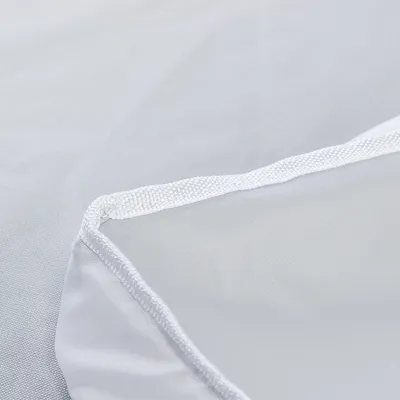 Gros plan sur un tissu blanc avec bordure cousue, matière synthétique visible. Aucun logo ni texte apparent.