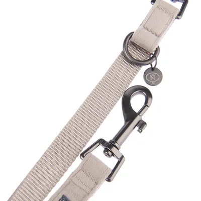 Beige Hundeleine mit Metallkarabiner, schwarzem Ring und Anhänger mit NT-Logo.
