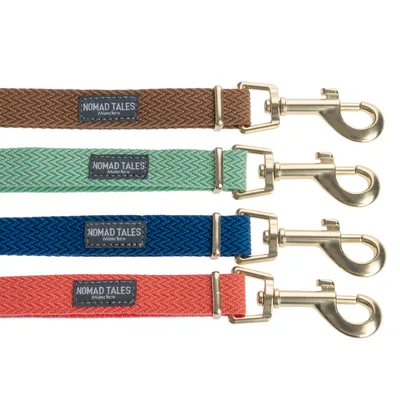 Quatre laisses en tissu avec mousqueton métallique, étiquettes visibles : NOMAD TALES München, couleurs marron, vert, bleu et orange.