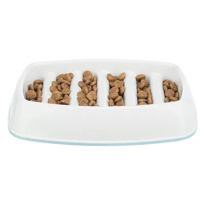 White feeding bowl with multiple vertical compartments, filled with brown dry food pieces.