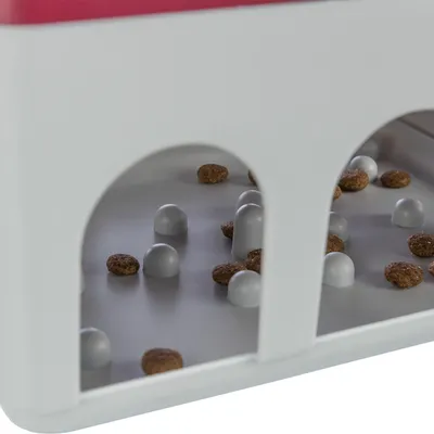 Detail plastového boxu s obloukovými otvory, uvnitř šedé výstupky a rozptýlené granule.