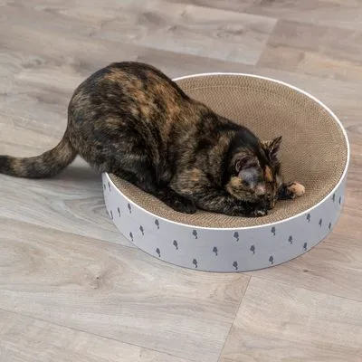 Kat op ronde krabkarton met witte zijkant en grijze boompatronen, geplaatst op houten vloer. Materiaal: karton.