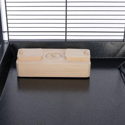 Juguete de madera con tres elementos móviles sobre superficie de metal negra, adecuado para animales pequeños.