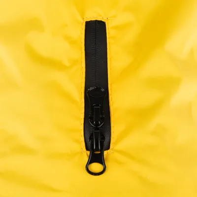 Primo piano di una cerniera nera su tessuto giallo, possibile parte di un prodotto in materiale idrorepellente.