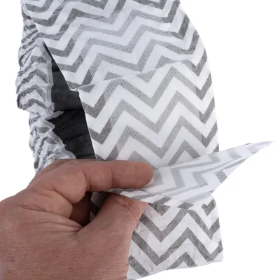 Hand showing the elastic structure and zigzag pattern of a grey disposable nappy with adhesive closure.