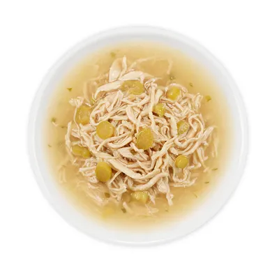 Close-up of a bowl with shredded chicken and green peas in broth.