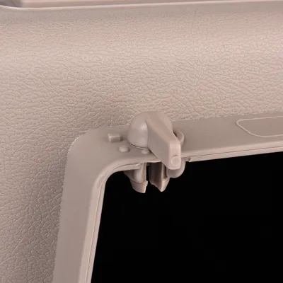 Close-up van een beige kunststofsluiting op een product, toont de structuur en mechaniek van de clip.