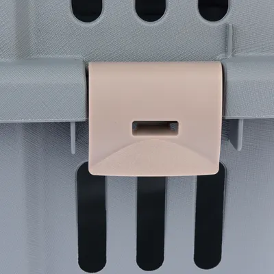 Nahaufnahme eines beigen Verschlusses an einer grauen Transportbox mit Lüftungsschlitzen.