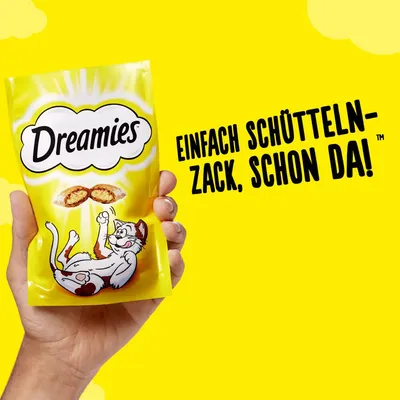 Упаковка Dreamies с изображением кота и лакомства; на упаковке текст на немецком: 'Einfach schütteln – zack, schon da!'.