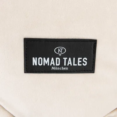 Nomad Tales München. Schwarzes Label mit weissem Schriftzug auf beigem Hintergrund.