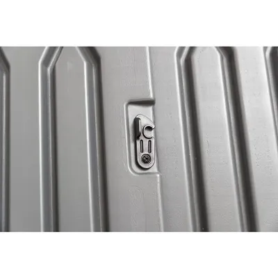 Zbliżenie na metalowy zatrzask zamontowany na szarej, żłobionej powierzchni z tworzywa sztucznego. Widoczna śruba mocująca.