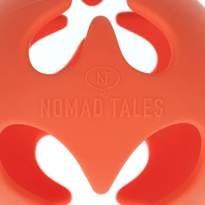 Jouet orange en plastique avec l’inscription visible « NOMAD TALES » et le sigle NT sur la surface.