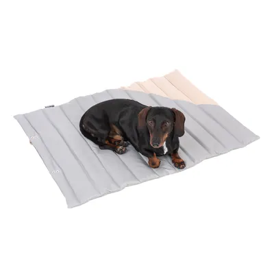 Hund liegt auf grauer und beiger Matte mit gestepptem Design. Produkt zeigt Nutzung als Liegefläche für Haustiere.