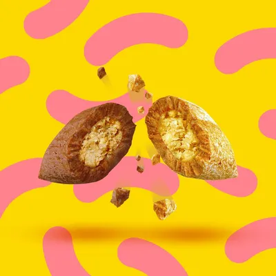 Gros plan sur deux croquettes ouvertes avec une coque croustillante et une garniture crémeuse, fond jaune à motifs roses.