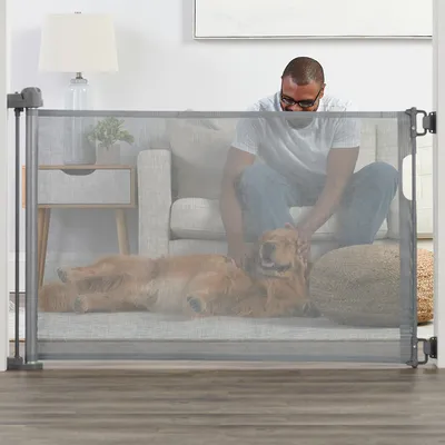 Barrière de sécurité en maille installée dans un salon, avec un grand chien allongé derrière la barrière et une personne assise sur un canapé.