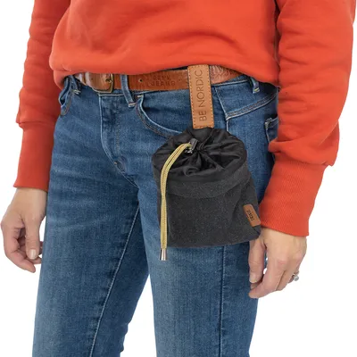 Pose med snorelukning, fastgjort til bælte med læderstrop 'BE NORDIC', båret af person i jeans og rød sweater.