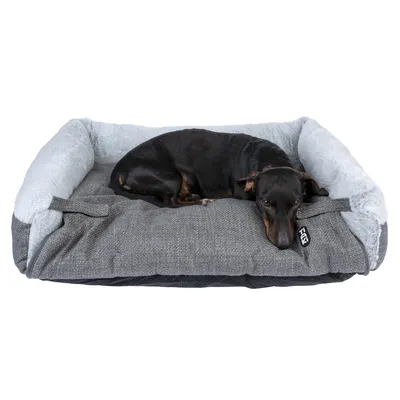 Schwarzer Hund liegt auf einem grauen Hundebett mit weichem, hellgrauem Rand und sichtbarem TIAKI-Logo.