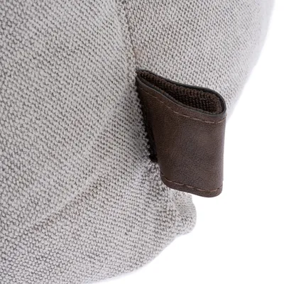 Detailaufnahme eines beige strukturierten Stoffes mit brauner Lederlasche.