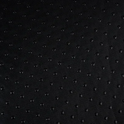 Surface en tissu noir avec points antidérapants visibles, vue rapprochée du matériau.