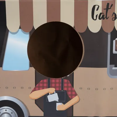 Ilustrácia predajného stánku s nápisom 'Cat's', oknom a predavačom v červenej košeli, čiernej zástere, drží šálku. Viditeľný okrúhly výrez v obrázku.