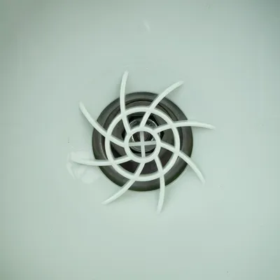 Close-up of a white plastic grid with a black metal ring, possibly part of a filter system or cover.